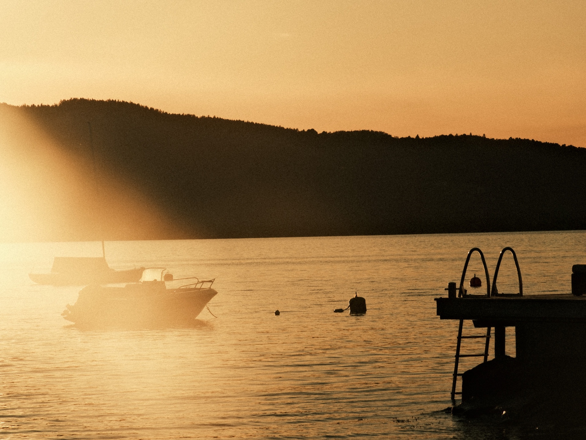 Boats silhouetted against an orange sunset over the Oslo fjord.