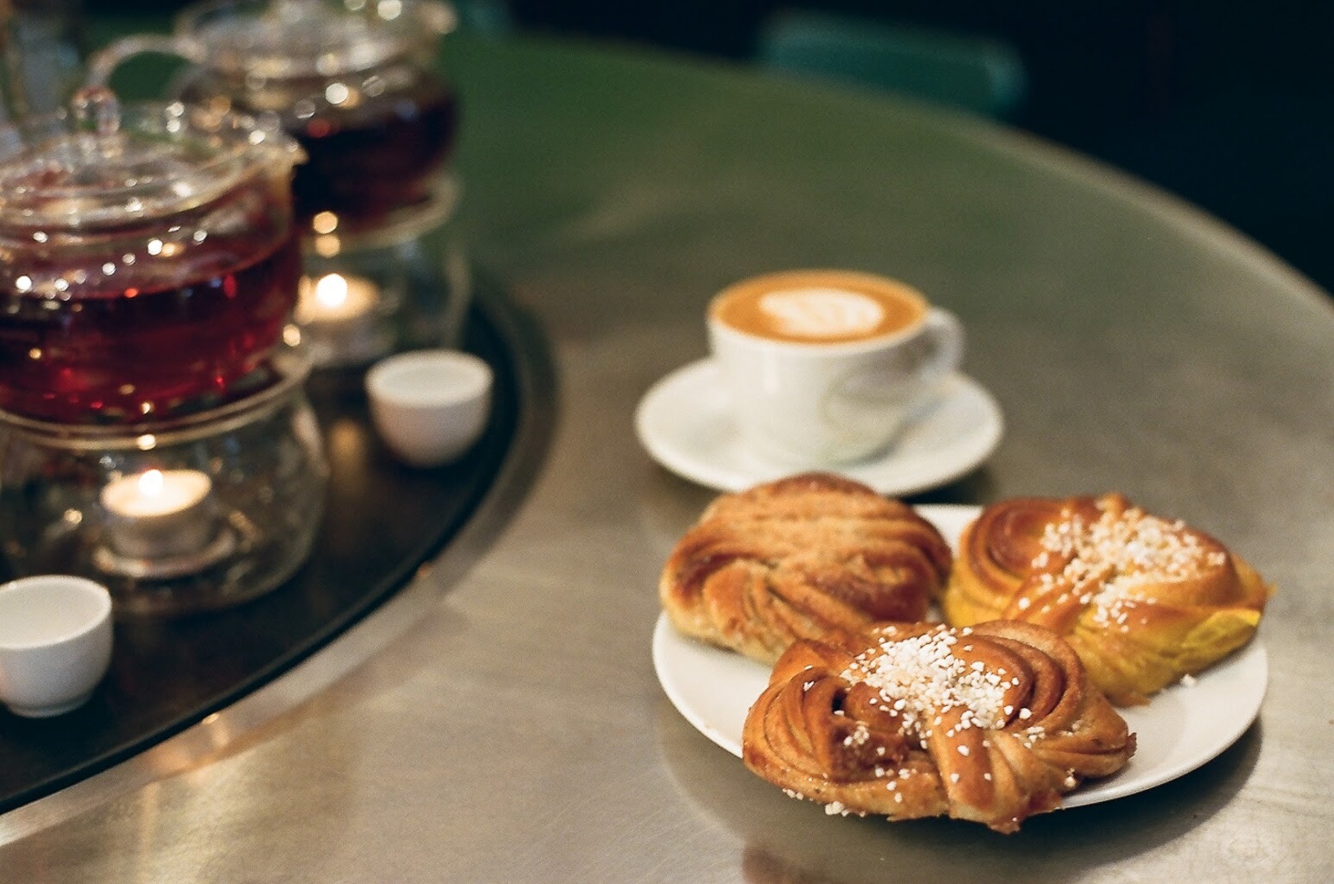 Cardamom buns and a flat white on a marble café table.